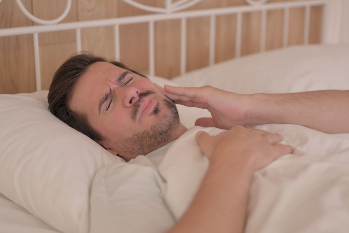 uomo che fa fatica a dormire col mal di denti