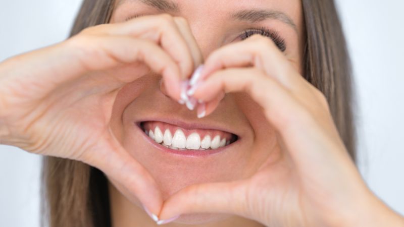 donna felice dopo sbiancamento fa il segno del cuore con le mani