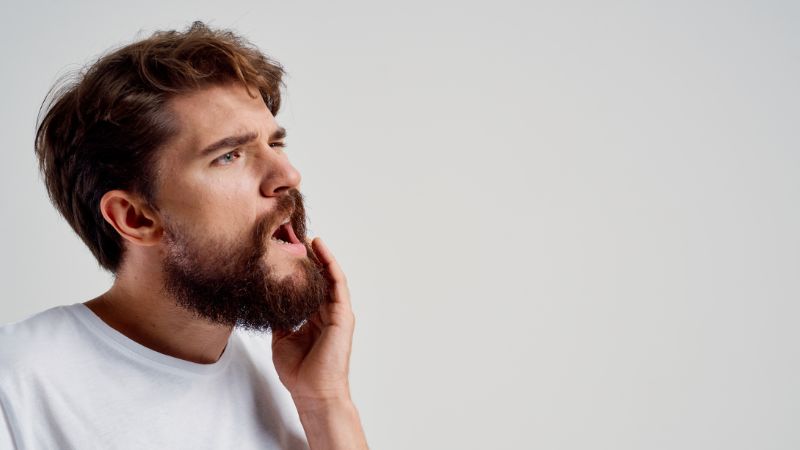 impianto dentale fallito, uomo si tocca la parte dolente