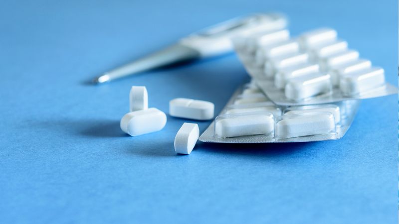 Compresse di un farmaco antinfiammatorio e un blister su uno sfondo blu. L'immagine rappresenta la terapia farmacologica utilizzata per controllare il dolore e il gonfiore nel periodo post-operatorio di un intervento di implantologia dentale