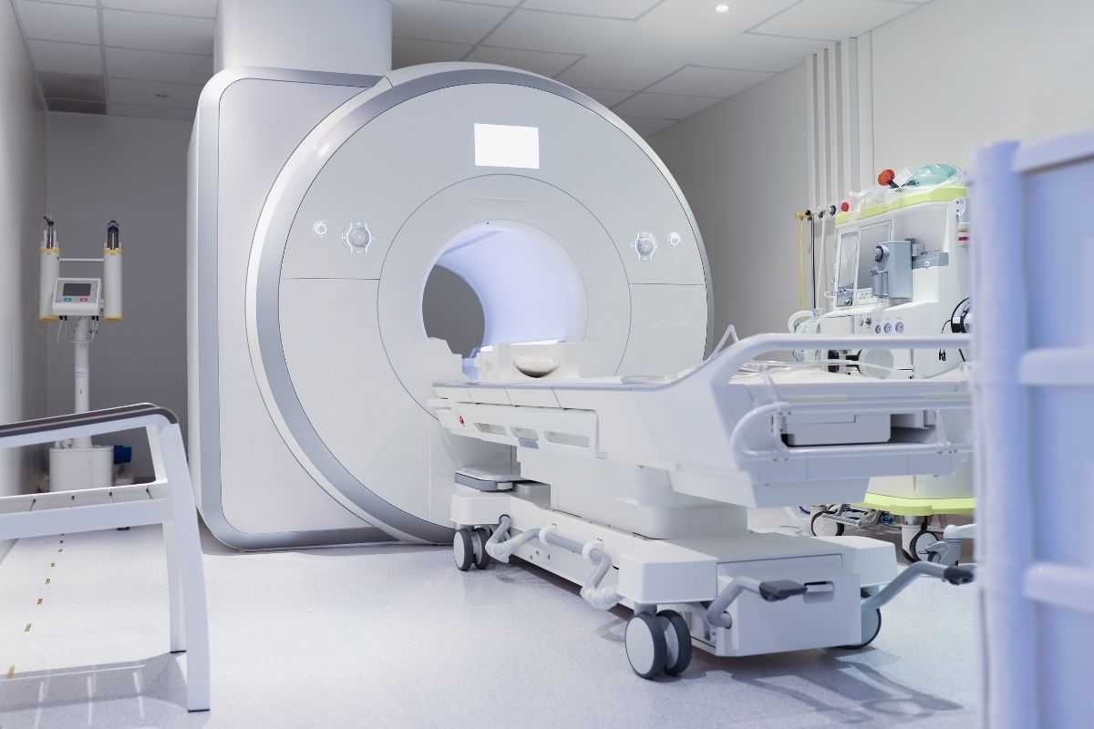 Sala diagnostica di un ospedale con un moderno macchinario per la risonanza magnetica. L'immagine mostra il tunnel del magnete e il lettino vuoto, introducendo l'ambiente in cui si discute la compatibilità con gli impianti dentali